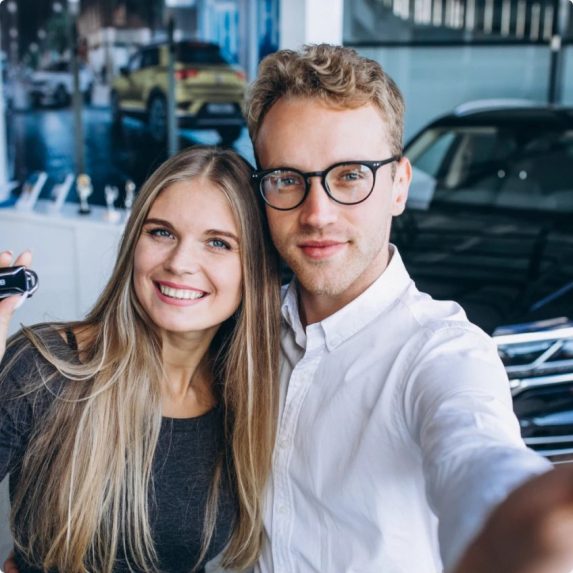 Para robiąca sobie selfie z kluczykiem w salonie samochodowym