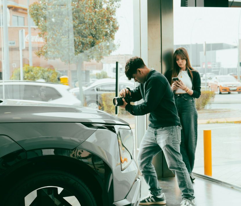 Man photographs car while woman watches