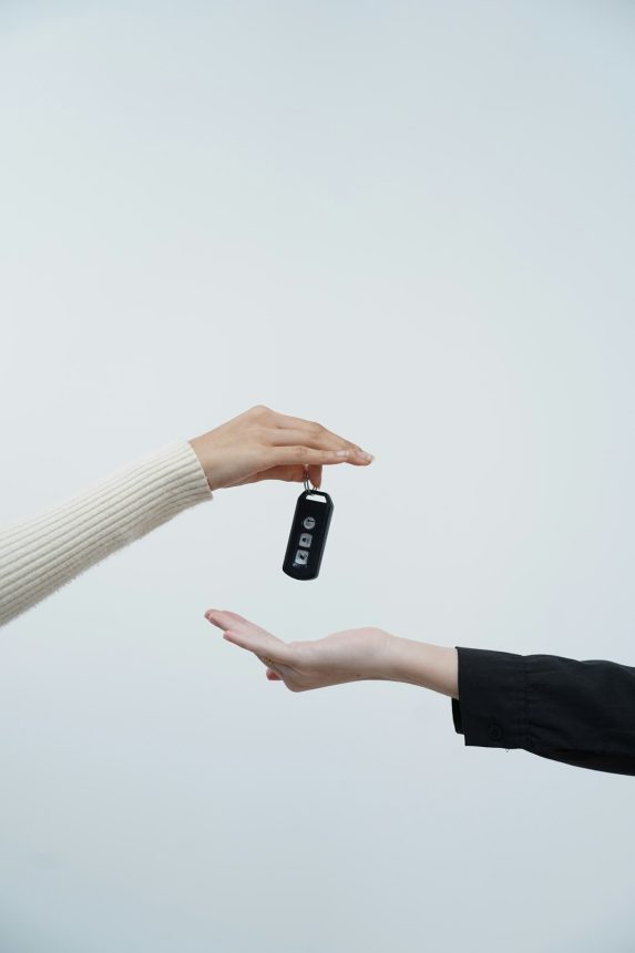 Hands exchanging car keys against a white background