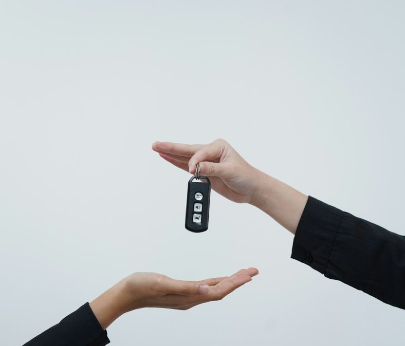 Hands exchanging a car key against a light background