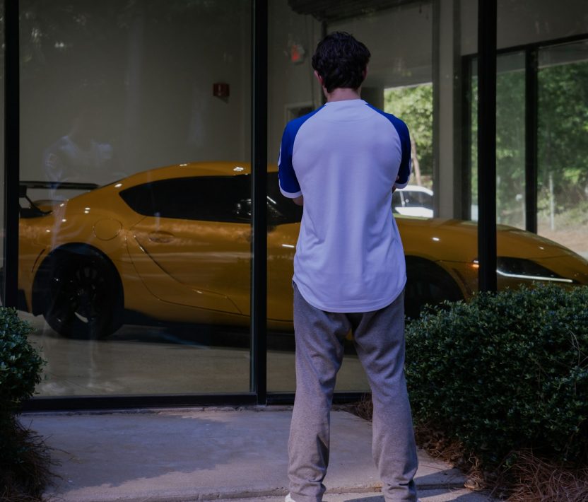 Man looking at a yellow sports car through window