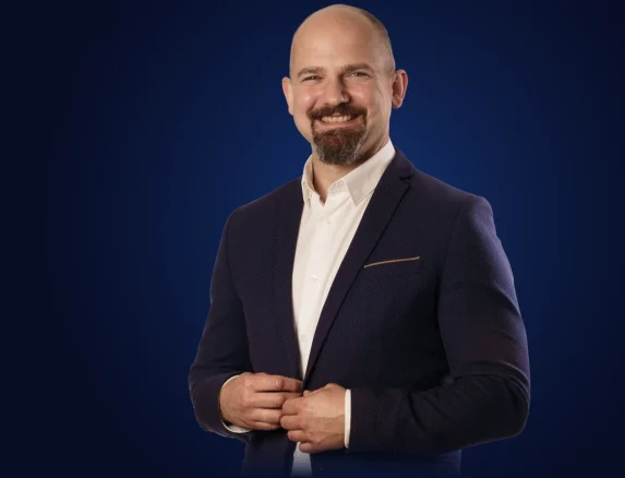 Marek Ejsmont, główny doradca, uśmiechnięty w granatowej marynarce